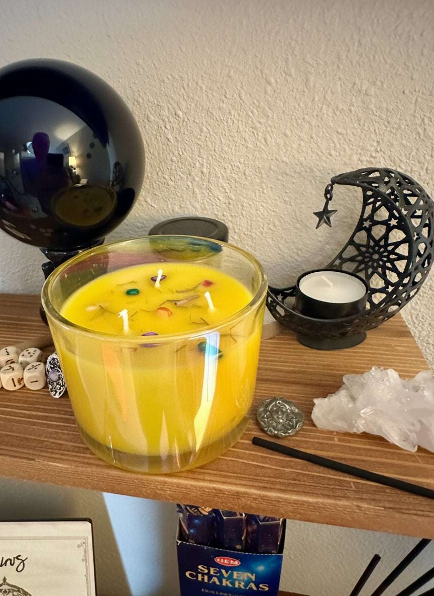 Yellow candle with decorative elements on a wooden surface with decorative items. With colored fluorite, and lemongrass.