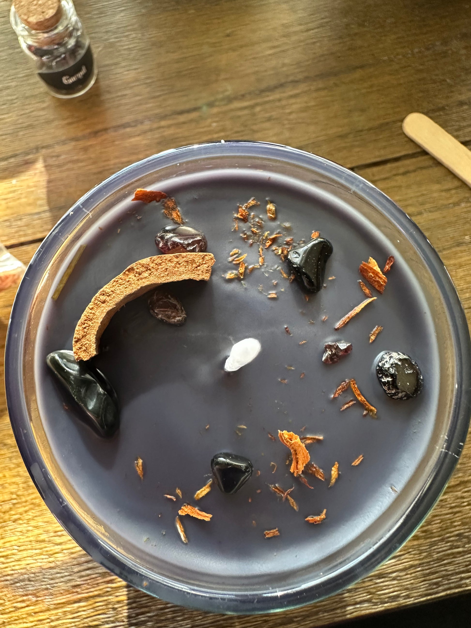 Close-up of a dark beverage with floating ingredients in a clear cup on a wooden surface